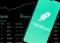 Imagen de un teléfono inteligente con la aplicación Robinhood abierta sobre un fondo de tablero de acciones y gráficos – Mundo Chido
