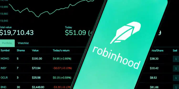 Imagen de un teléfono inteligente con la aplicación Robinhood abierta sobre un fondo de tablero de acciones y gráficos – Mundo Chido