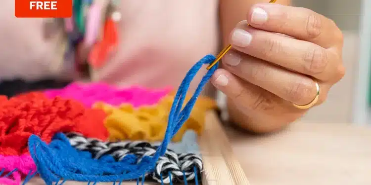 Mano tejiendo con lana azul en un telar de colores con etiqueta 'Free' en la esquina.