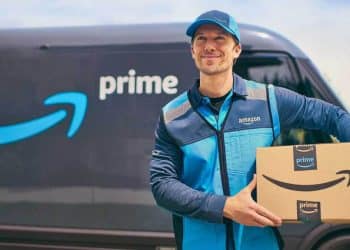 Repartidor de Amazon Prime sosteniendo un paquete frente a una furgoneta con logo de Prime. Imagen usada en Mundo Chido para ilustrar los beneficios de Amazon Prime.